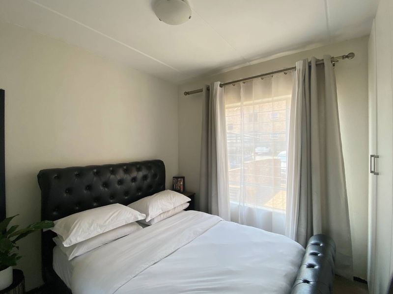 A cozy bedroom featuring a built-in wardrobe and a window with installed curtain rods, providing natural light.