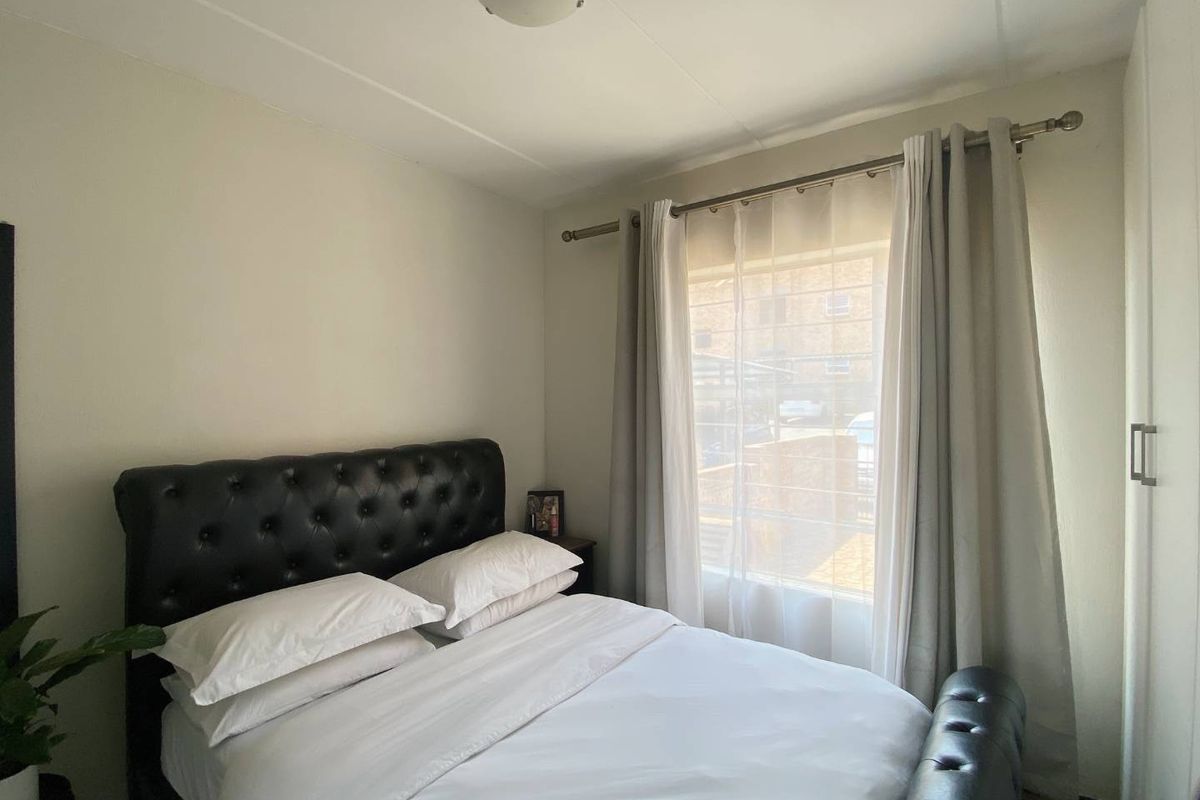 A cozy bedroom featuring a built-in wardrobe and a window with installed curtain rods, providing natural light.