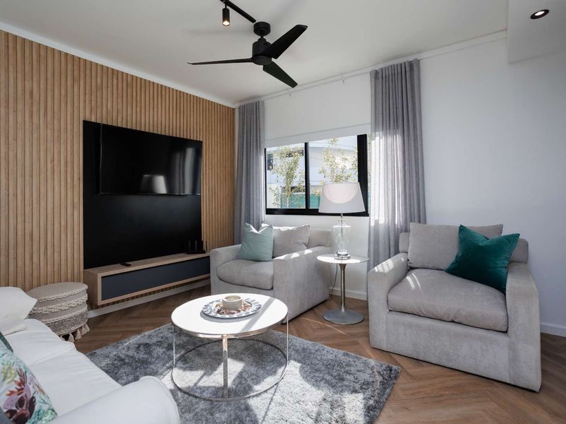 Modern living room featuring a stylish timber slat feature wall, herringbone flooring, and a contemporary ceiling fan.