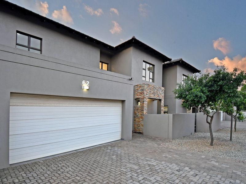 Modern double-storey townhouse facade featuring a paved driveway, double garage, and attractive stone cladding detail at the entrance.