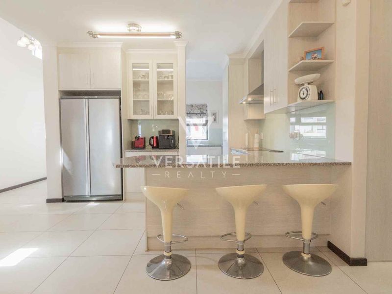 Modern kitchen featuring light-toned cabinetry, granite countertops, a breakfast bar, and integrated storage, offering a clean and functional culinary space.