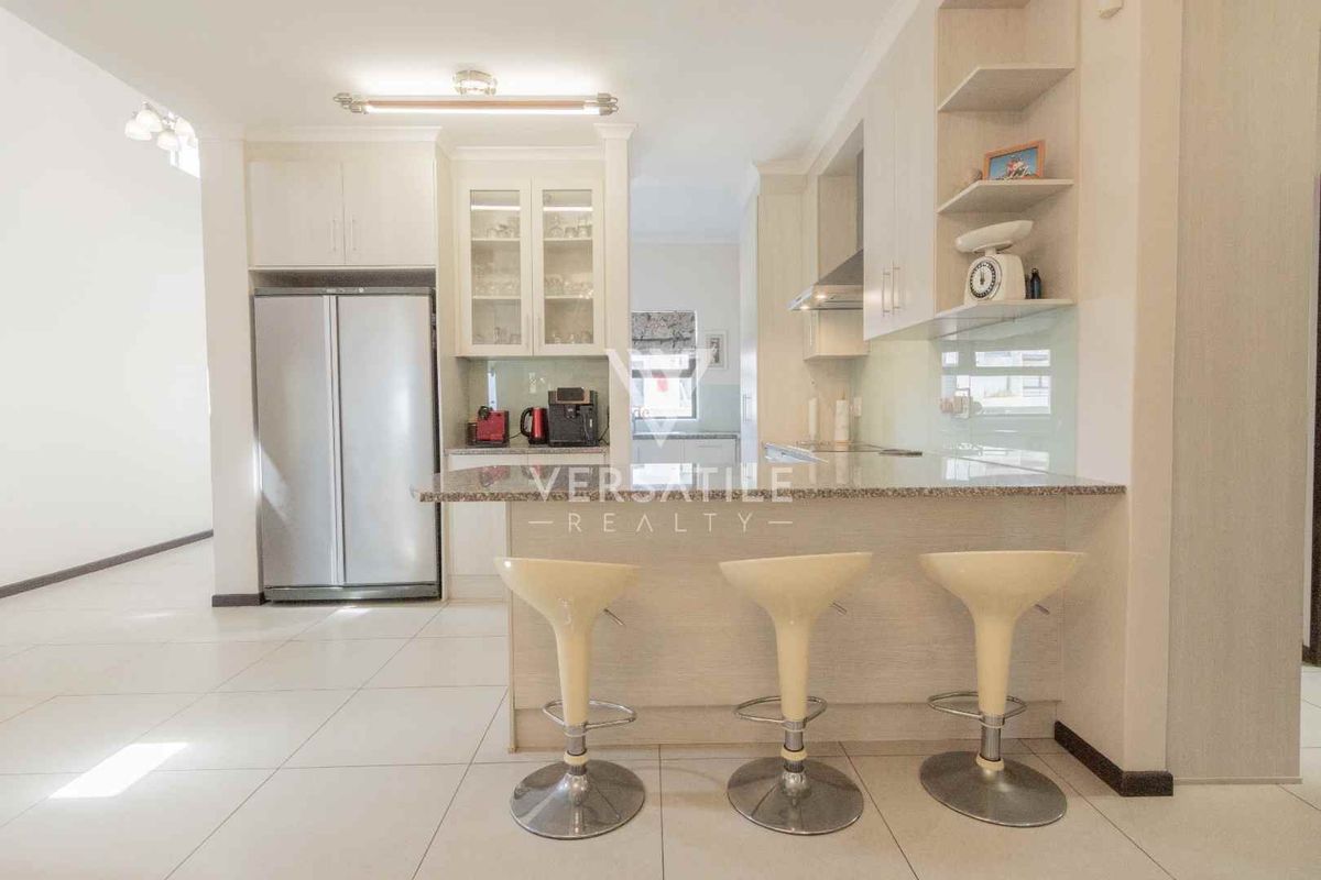Modern kitchen featuring light-toned cabinetry, granite countertops, a breakfast bar, and integrated storage, offering a clean and functional culinary space.