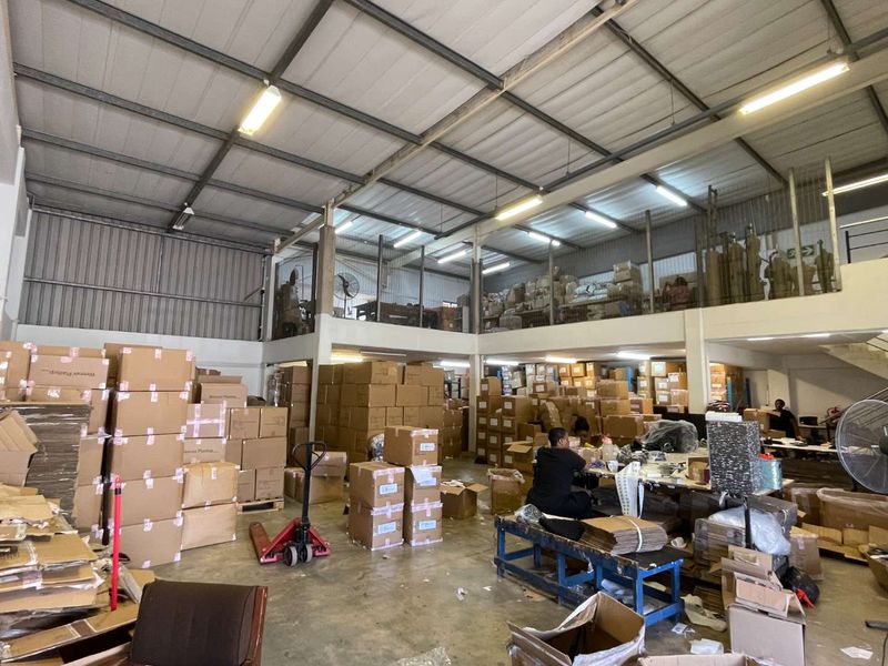 Industrial warehouse space featuring high ceilings with exposed steel trusses, a mezzanine level, and durable concrete flooring suitable for storage or light manufacturing.