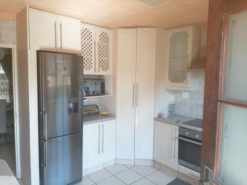 A functional kitchen featuring light-toned built-in cabinetry, tiled flooring, a built-in oven with hob, and a tiled backsplash.