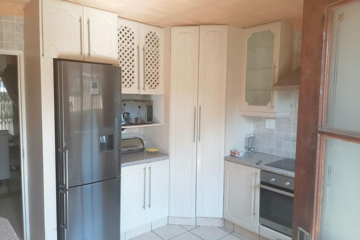 A functional kitchen featuring light-toned built-in cabinetry, tiled flooring, a built-in oven with hob, and a tiled backsplash.