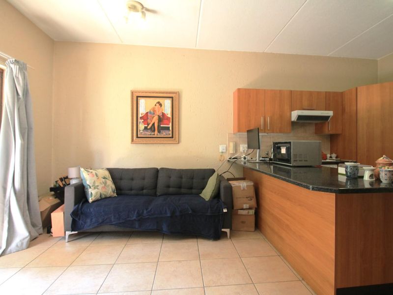Open-plan living area featuring a kitchen with wood-finish cabinetry, granite countertops, and tiled flooring throughout.