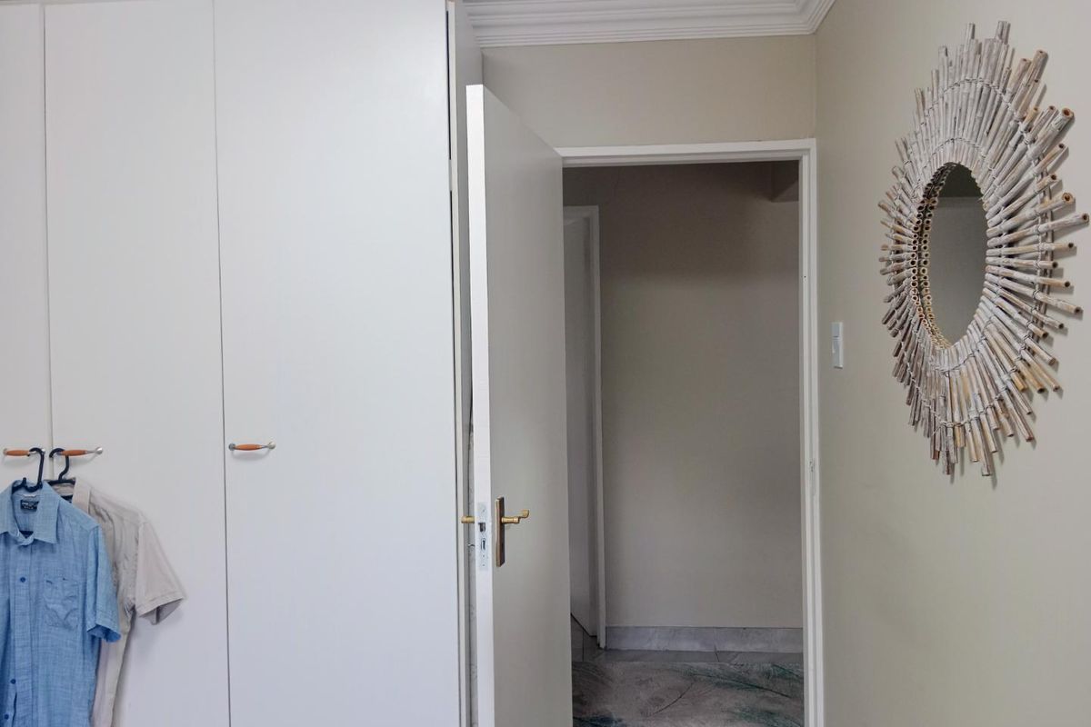 A bedroom interior featuring built-in white cupboards, crown molding, and a doorway leading to an adjacent space.