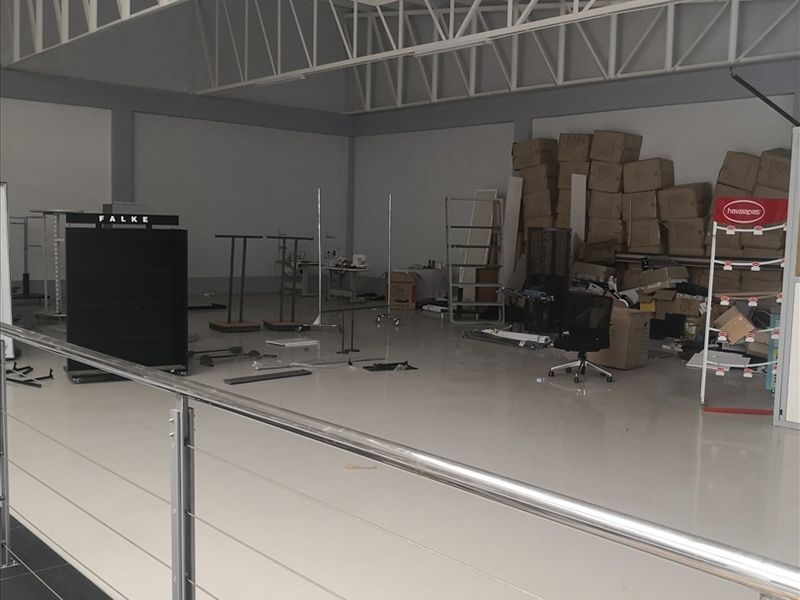 Spacious industrial utility area featuring high exposed steel roof trusses, polished epoxy flooring, and a modern stainless steel cable railing overlooking the lower level.