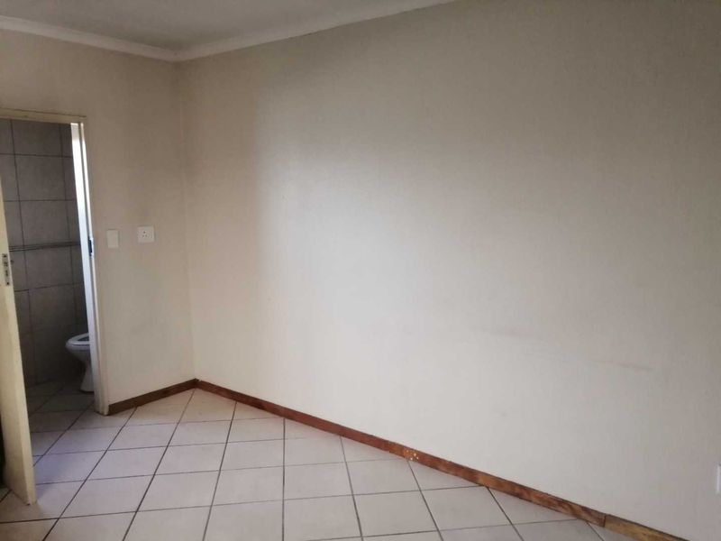 An empty bedroom featuring tiled flooring and direct access to an adjoining bathroom.