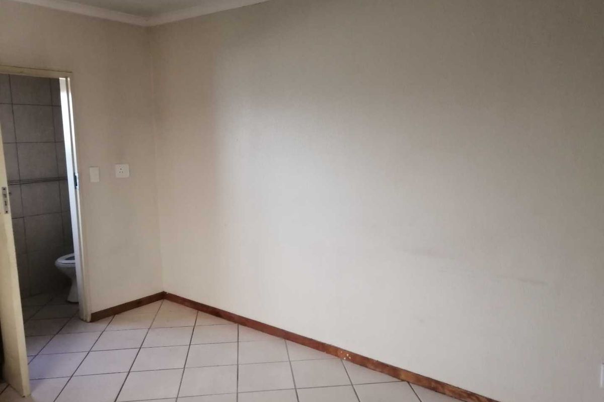 An empty bedroom featuring tiled flooring and direct access to an adjoining bathroom.