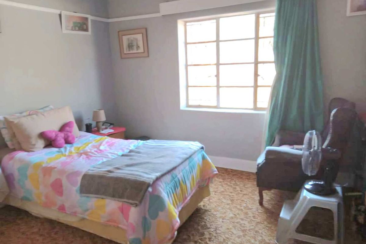 A bedroom featuring a classic steel-framed window, picture rail detailing, and carpeted flooring.