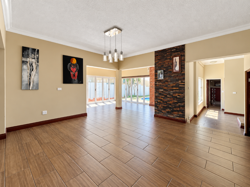 Spacious open-plan living area featuring wood-look tiled flooring, a striking stone feature wall, and large sliding glass doors providing access to the outdoor area.
