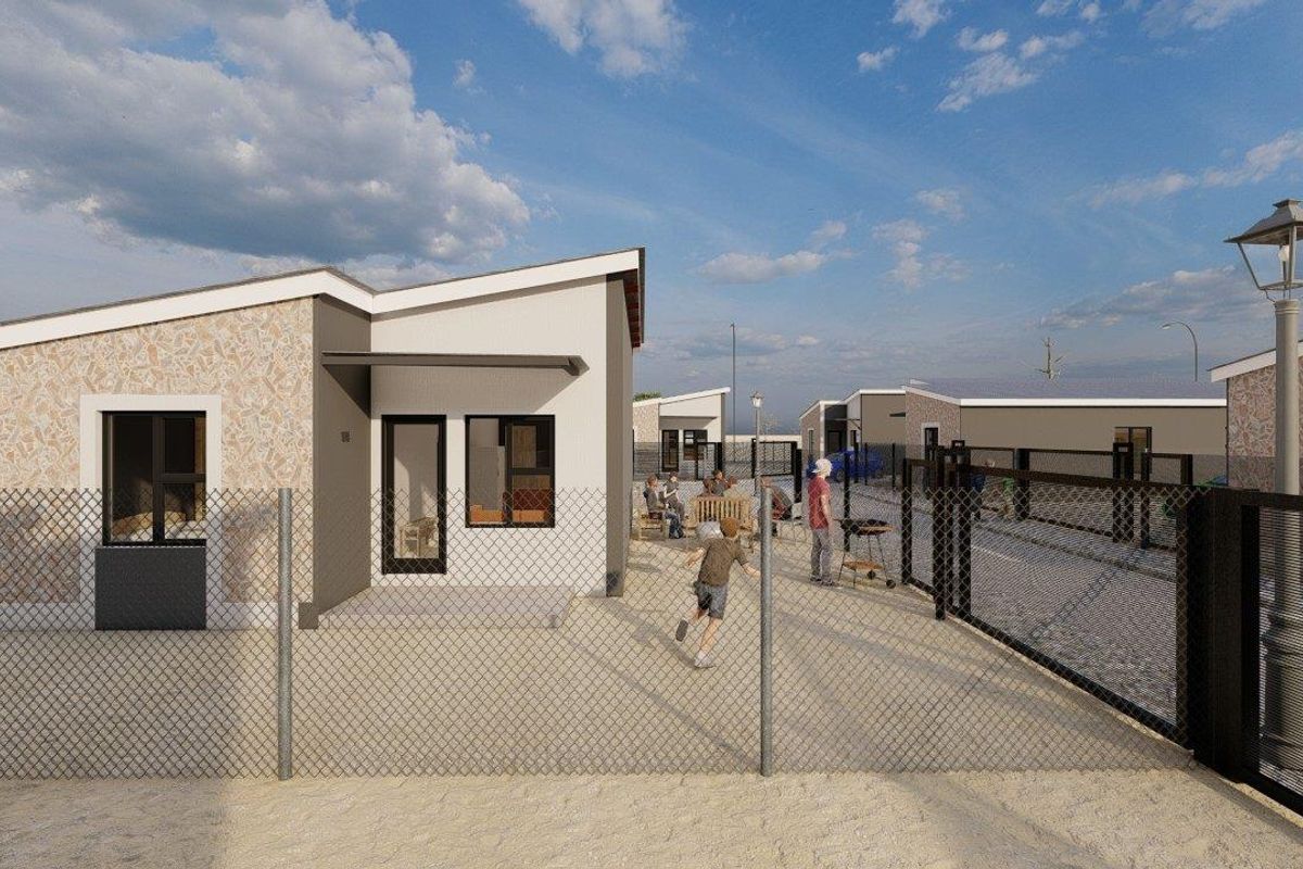 A modern townhouse exterior featuring stone cladding accents, a paved patio area, and secure perimeter fencing within a residential development.