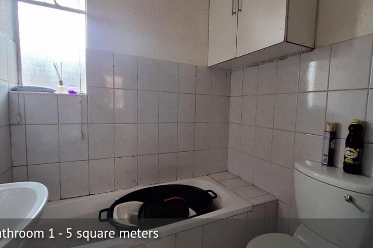 A compact bathroom featuring a bathtub, toilet, and wall-mounted storage cabinet with tiled wall finishes.