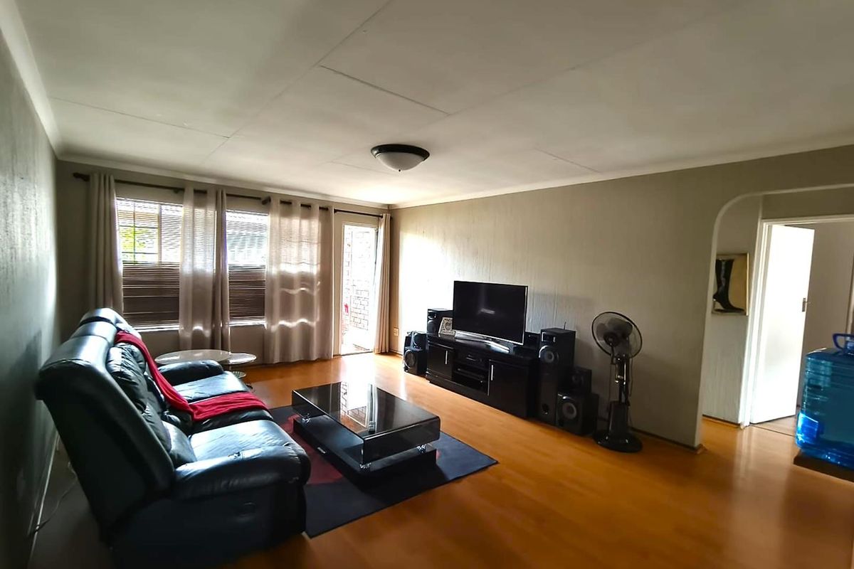A spacious living room featuring laminate flooring, neutral wall tones, and an arched entryway leading to adjacent areas.