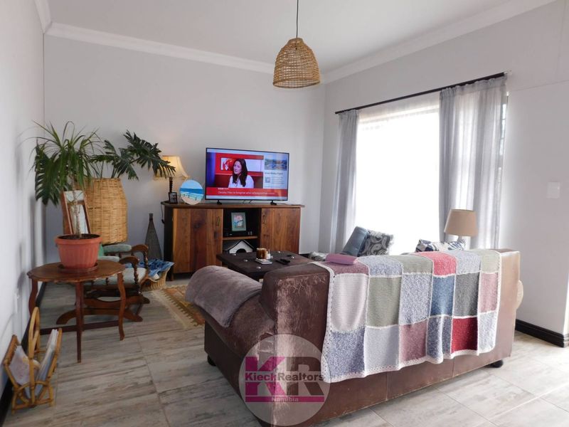 A comfortable living room featuring tiled flooring and neutral wall finishes, providing a bright and inviting space for relaxation.