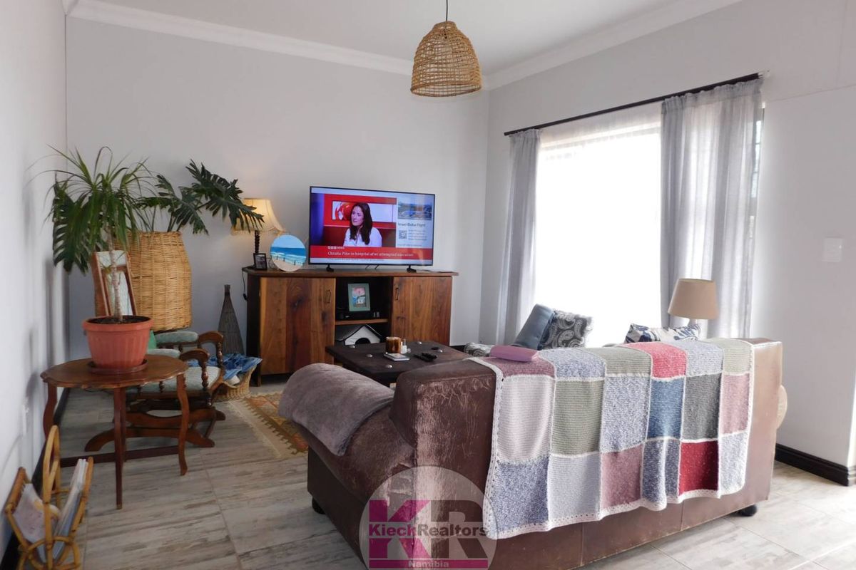 A comfortable living room featuring tiled flooring and neutral wall finishes, providing a bright and inviting space for relaxation.