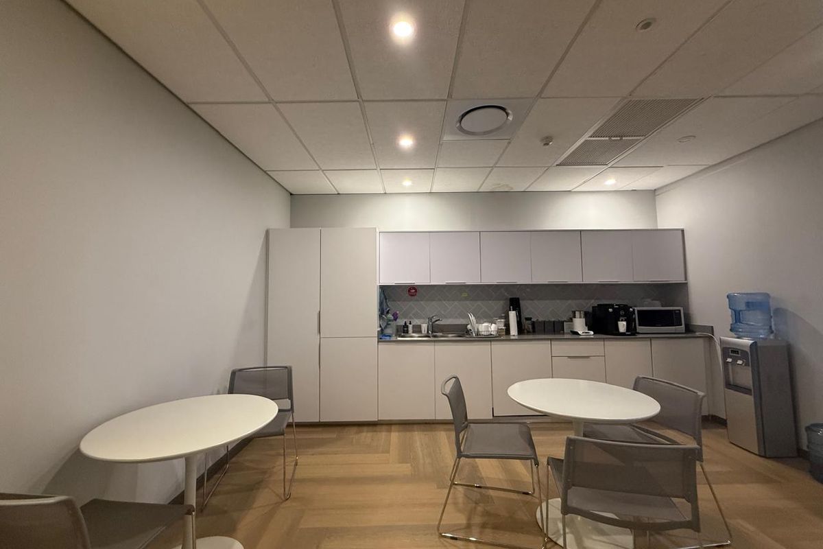 A functional office kitchenette featuring built-in cabinetry, a stainless steel sink, and integrated storage, set within a clean, professional workspace.