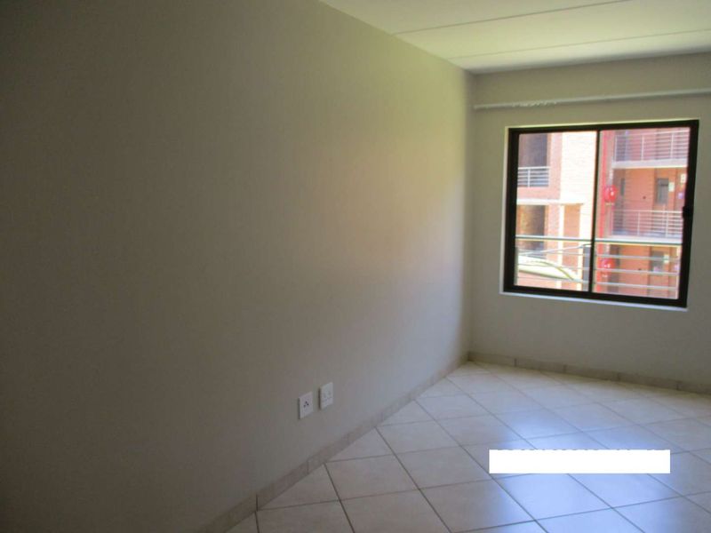 A vacant bedroom featuring neutral wall finishes, tiled flooring, and a window with an exterior view.