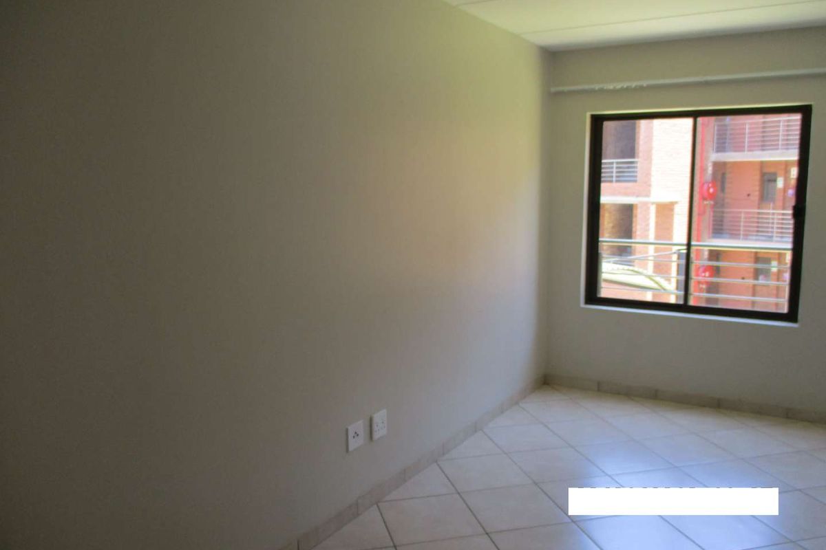 A vacant bedroom featuring neutral wall finishes, tiled flooring, and a window with an exterior view.