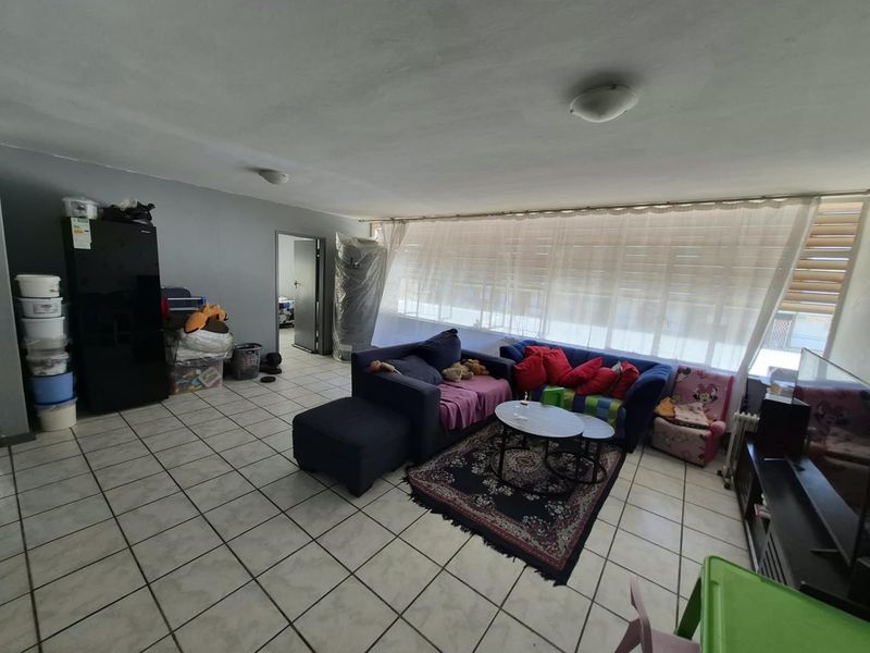 A spacious living area featuring ceramic floor tiles and large windows, offering a blank canvas for potential interior updates and modern styling.