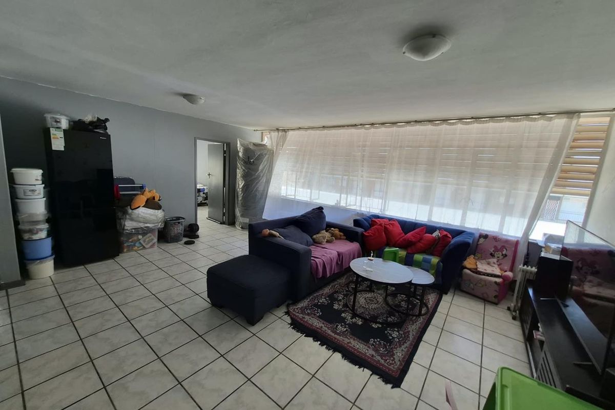 A spacious living area featuring ceramic floor tiles and large windows, offering a blank canvas for potential interior updates and modern styling.