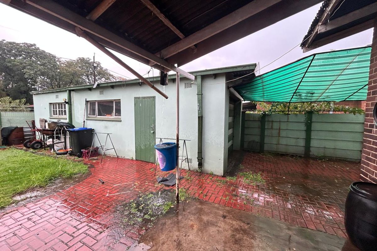 Rear exterior view of the property featuring a paved patio area, a detached outbuilding, and a green shade cloth structure.