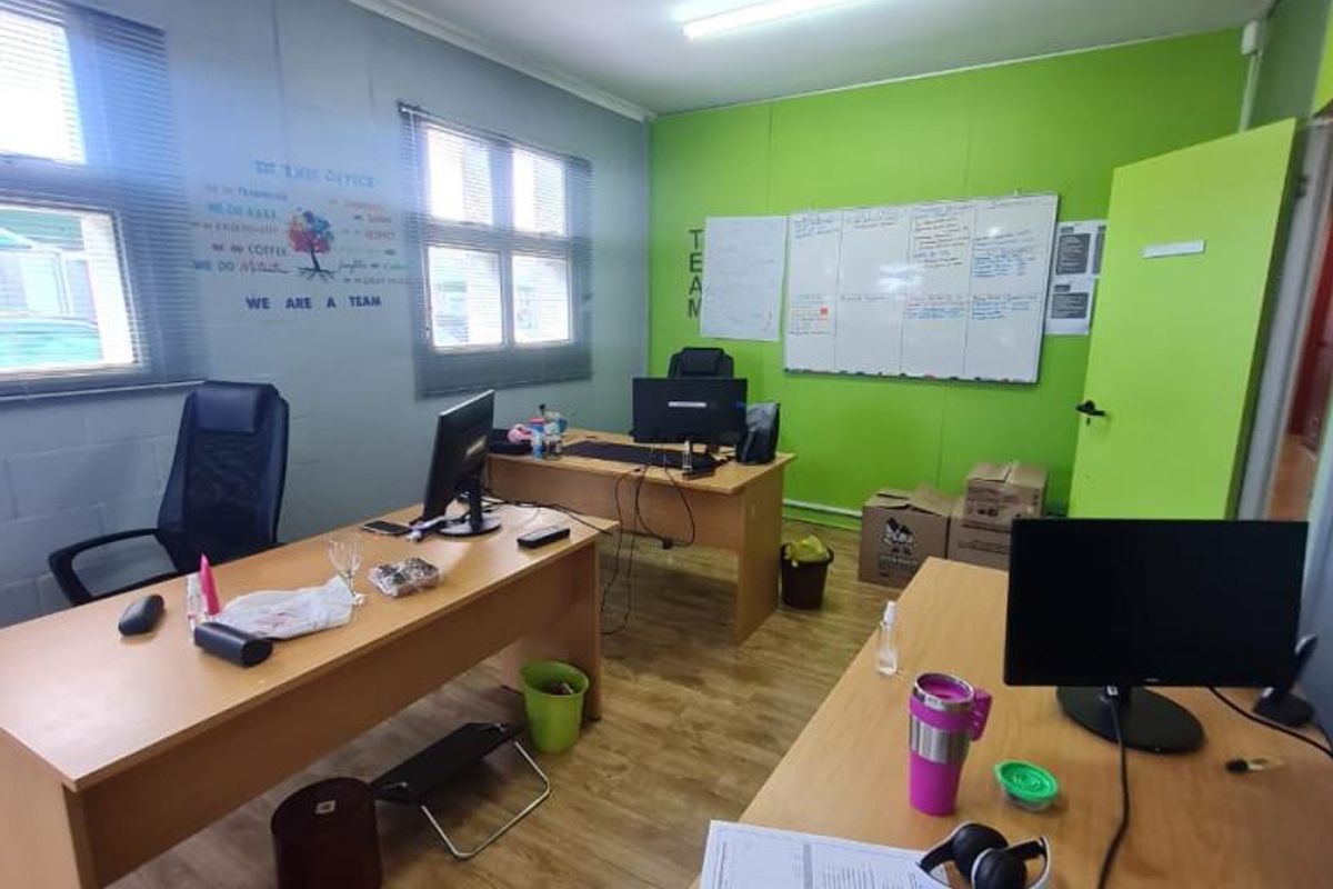 A functional office space featuring laminate flooring, large windows for natural light, and a wall-mounted whiteboard, suitable for a collaborative work environment.