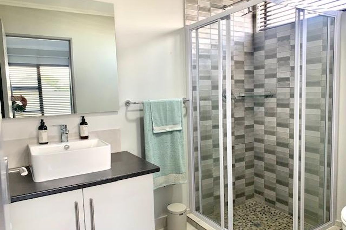 Modern bathroom featuring a sleek vessel sink vanity, a glass-enclosed shower with decorative mosaic tiling, and a large wall-mounted mirror.