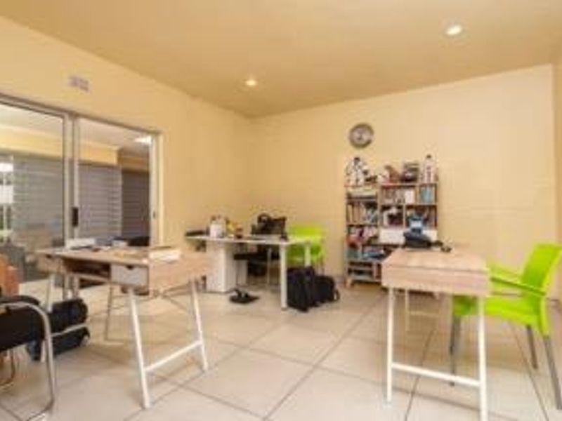 A functional office space featuring tiled flooring, recessed downlighting, and a large sliding glass door providing access to the exterior.