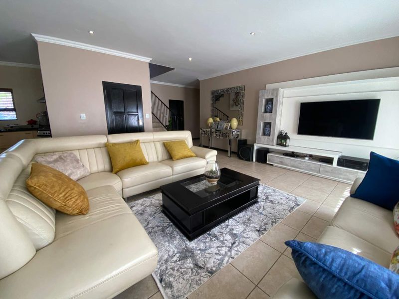 Spacious living room featuring tiled flooring, recessed downlights, and a custom built-in media unit, providing a comfortable and functional family space.