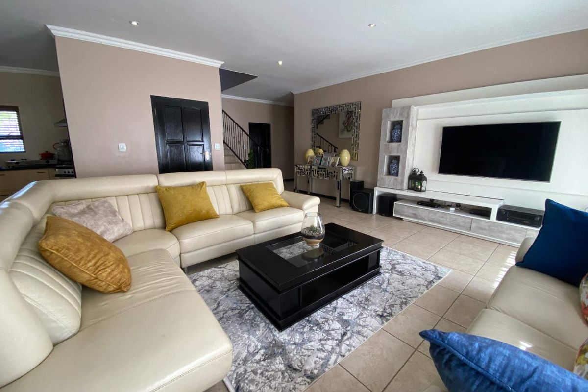 Spacious living room featuring tiled flooring, recessed downlights, and a custom built-in media unit, providing a comfortable and functional family space.