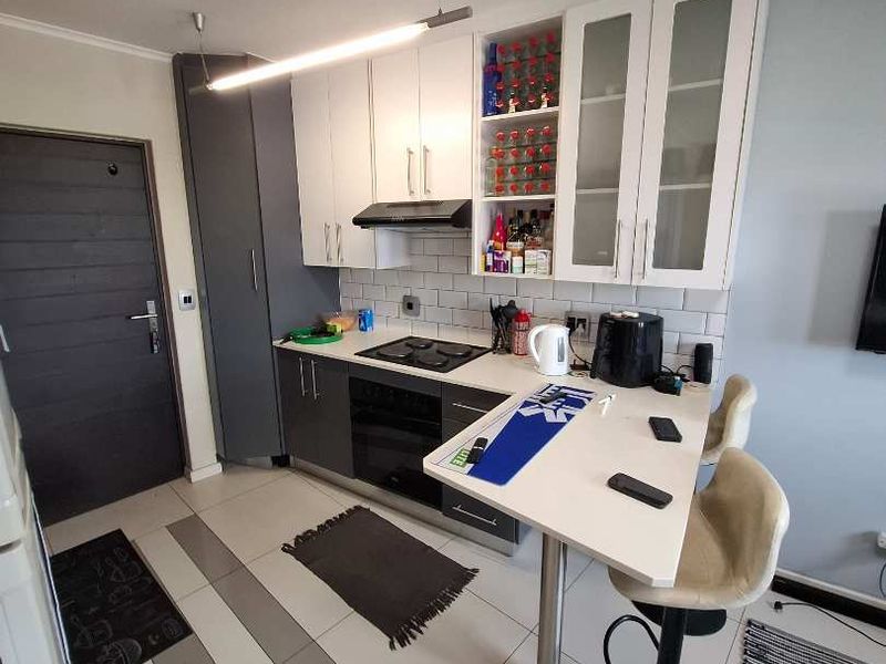 Modern kitchen featuring two-tone cabinetry, subway tile backsplash, integrated hob and oven, and a convenient breakfast bar for casual dining.