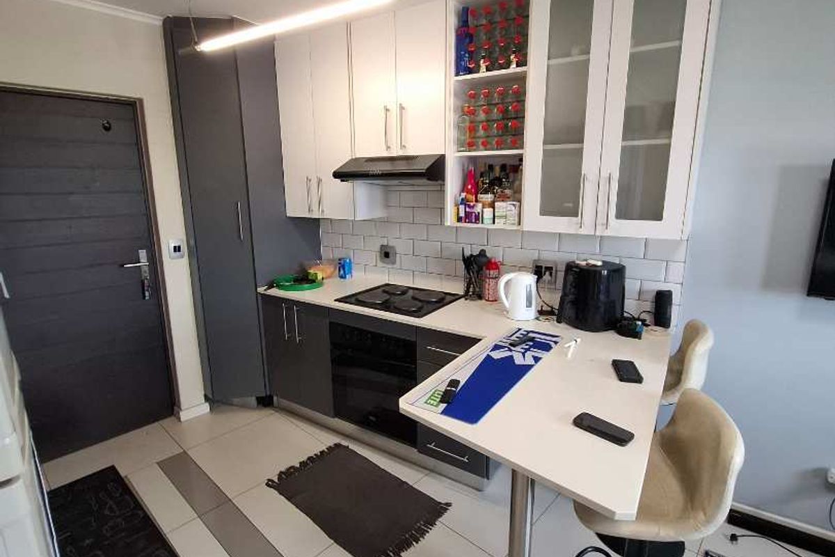 Modern kitchen featuring two-tone cabinetry, subway tile backsplash, integrated hob and oven, and a convenient breakfast bar for casual dining.