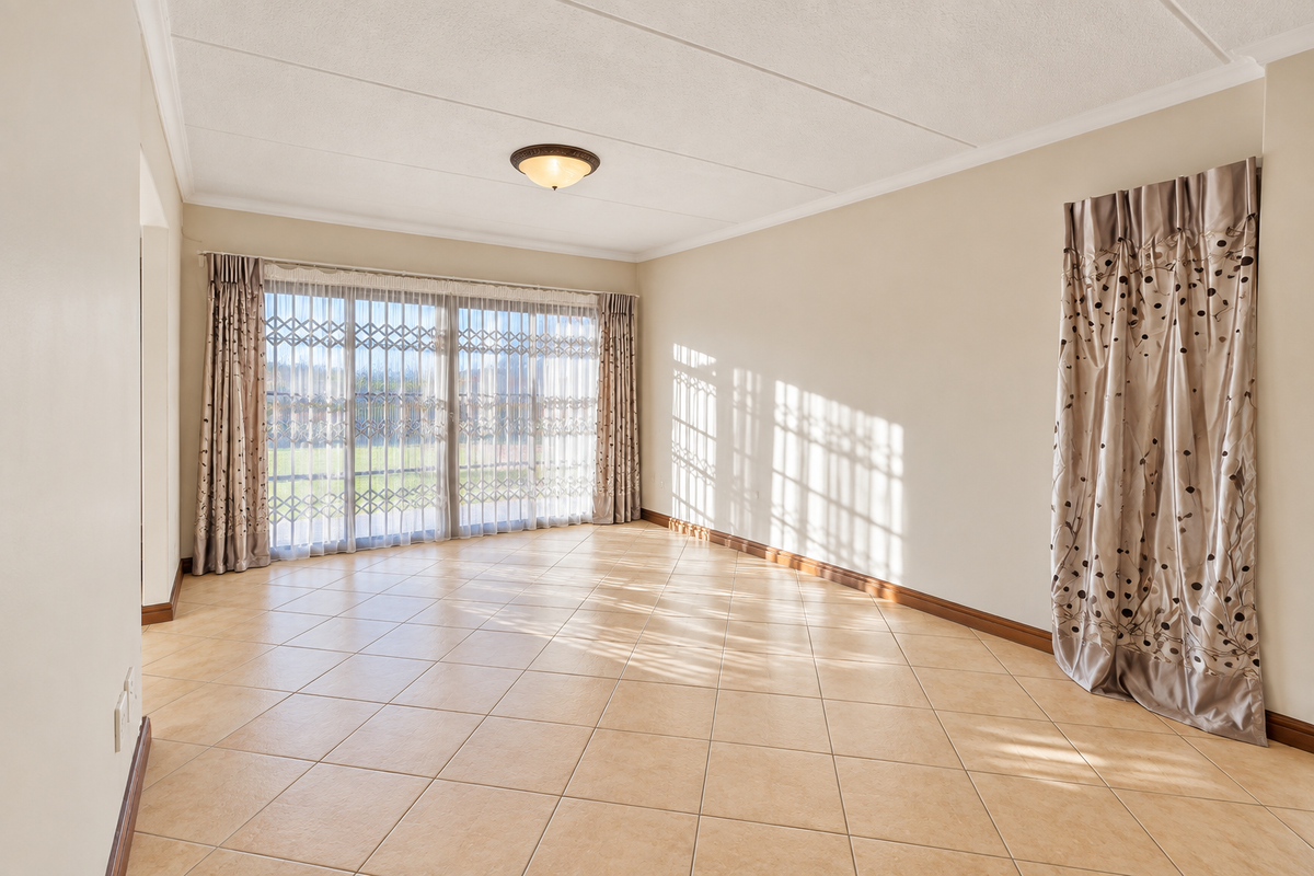 A bright and spacious living room featuring neutral ceramic tile flooring, large sliding glass doors with security gates, and a clean, minimalist aesthetic.