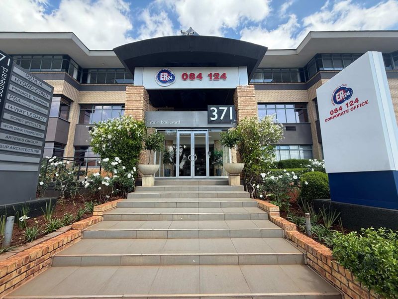 Front elevation of a commercial office building featuring a tiled entrance staircase, glass doors, and prominent corporate signage.
