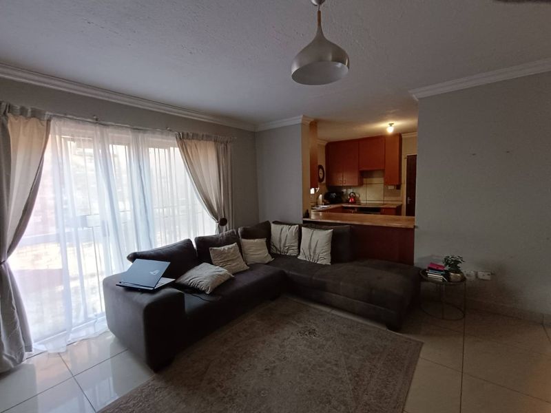Open plan living area featuring tiled floors, a breakfast bar, and direct access to a balcony, seamlessly connected to the kitchen space.