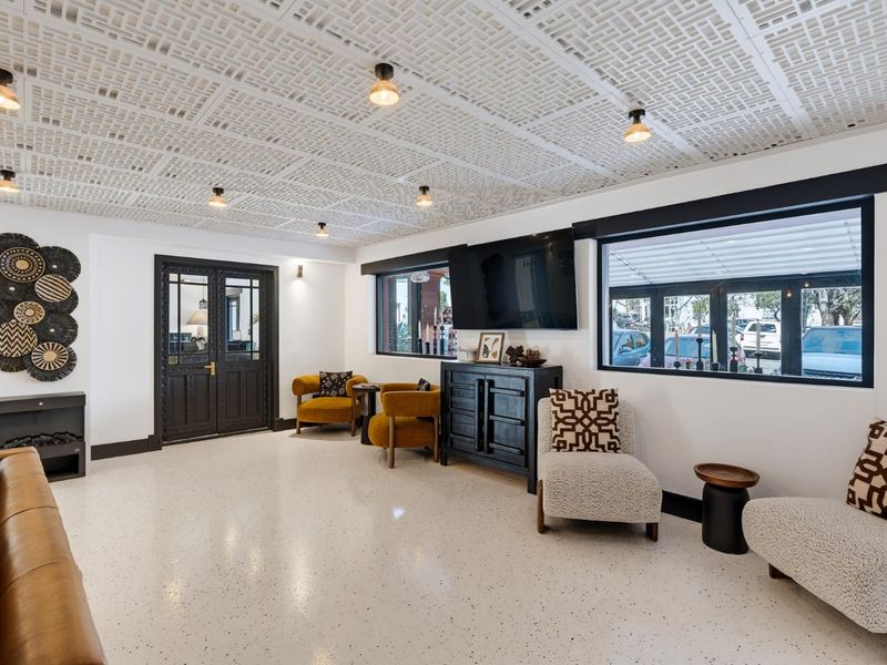 A well-lit retail lounge area featuring a unique decorative drop ceiling, polished epoxy flooring, and large windows providing natural light and street visibility.