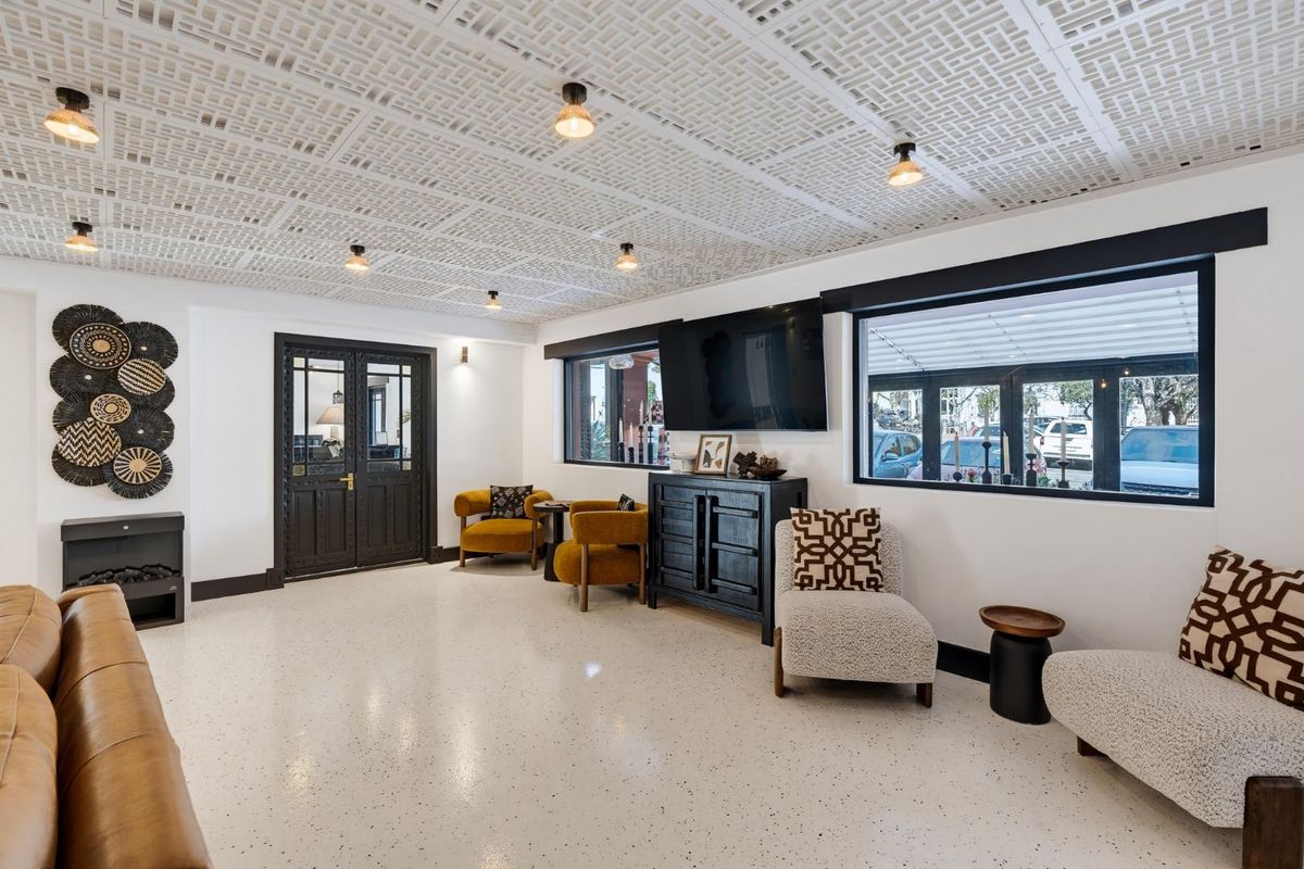 A well-lit retail lounge area featuring a unique decorative drop ceiling, polished epoxy flooring, and large windows providing natural light and street visibility.