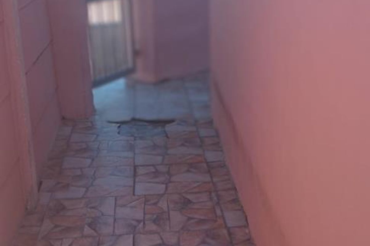 A narrow side passage featuring tiled flooring and a metal gate, providing access to the exterior area of the property.