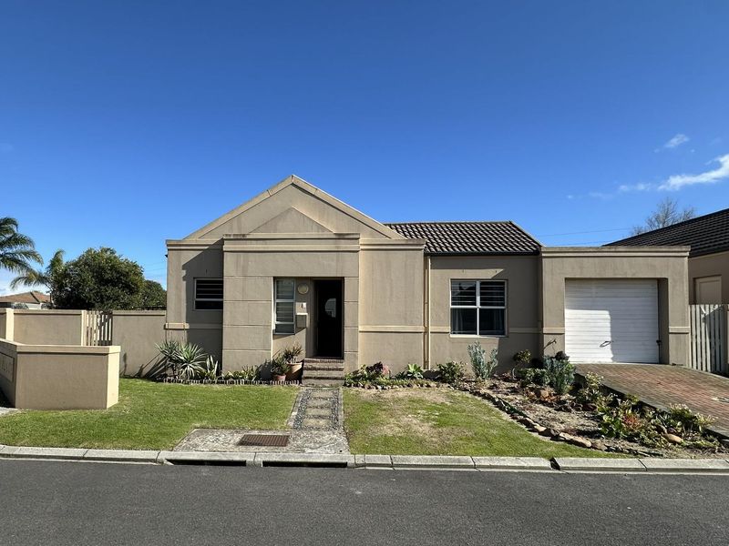 Front elevation of a townhouse featuring a single garage, paved driveway, and a landscaped front garden with a paved walkway to the entrance.