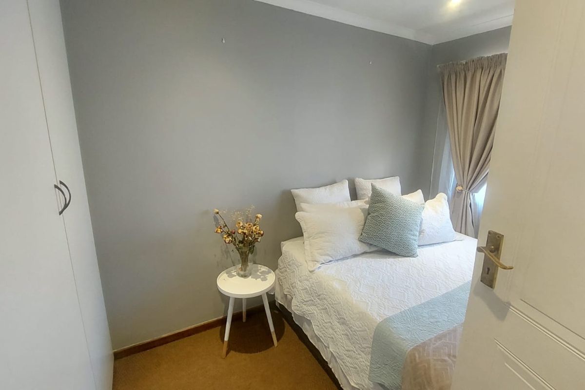 A compact bedroom featuring built-in wardrobes, neutral wall tones, and carpeted flooring, offering a functional and cozy living space.
