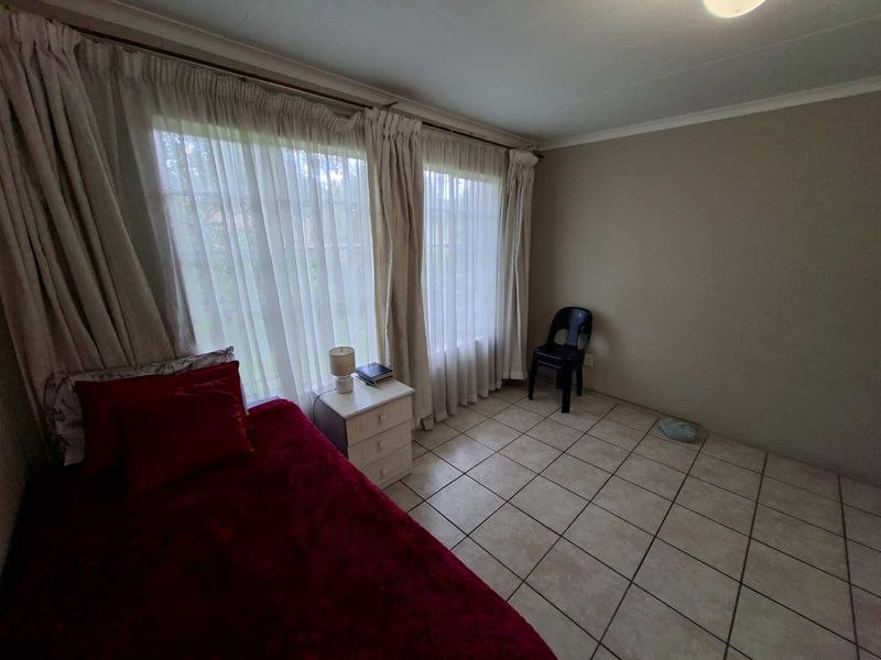 A bedroom featuring tiled flooring and large windows with curtain rails, offering a neutral base for personalization.