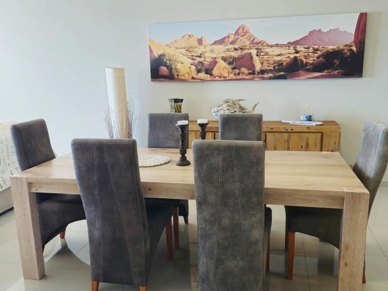 A bright dining room featuring polished tiled flooring and a neutral color palette, providing a clean and functional space for family meals.