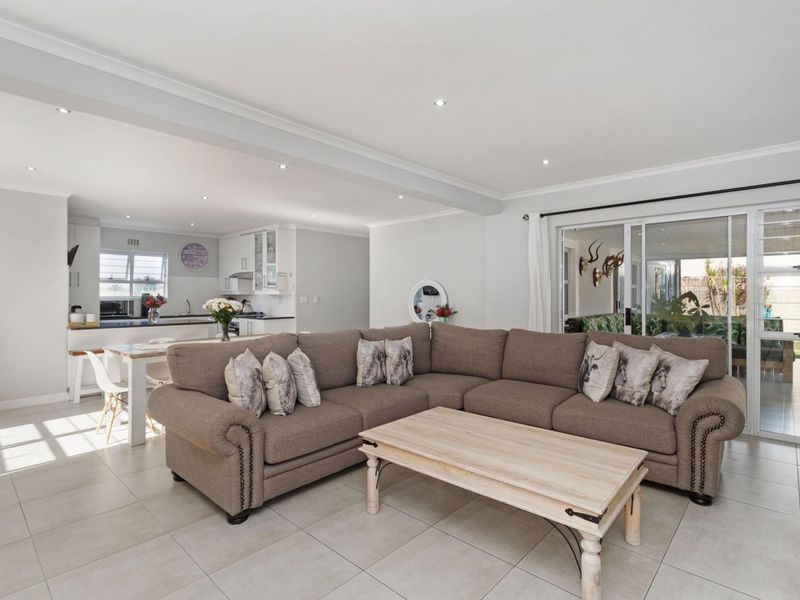 Spacious open-plan living area featuring tiled floors, recessed lighting, and seamless flow to the kitchen and outdoor patio through sliding glass doors.