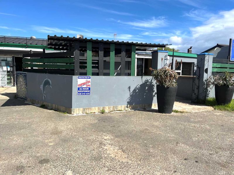 Front exterior view of the business premises featuring a perimeter wall, security gate, and a covered outdoor area.