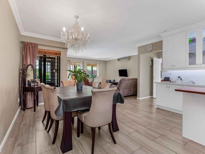 Spacious open-plan living and dining area featuring modern tiled flooring, built-in kitchen cabinetry, and a central island, creating a functional and cohesive living space.