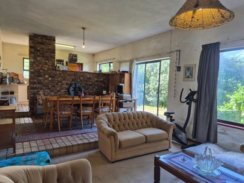Spacious open-plan living and dining area featuring an exposed brick fireplace, raised dining platform, and large sliding doors leading to the garden.