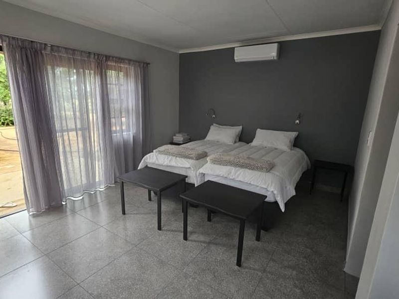 A well-maintained bedroom featuring tiled flooring, a split-system air conditioner, and a sliding glass door providing direct access to the outdoor area.