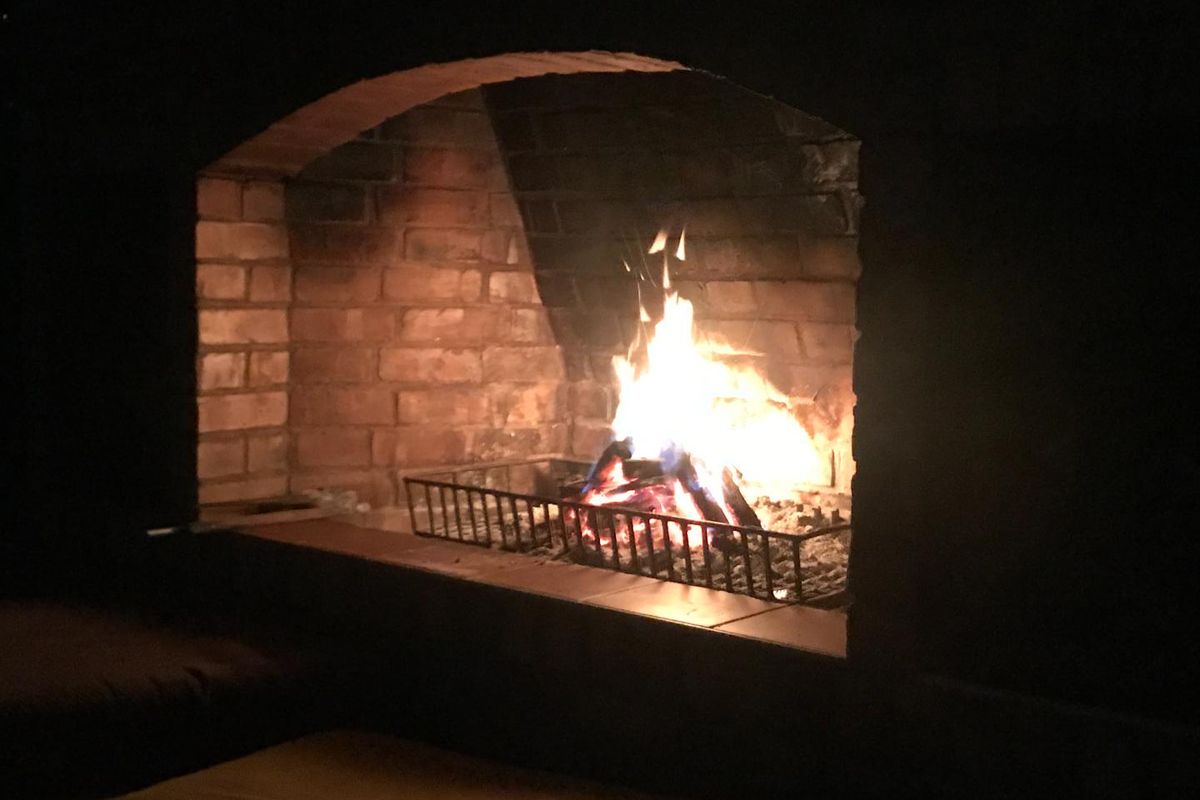 A traditional brick-built fireplace featuring an arched opening and a metal fire grate, creating a warm and inviting atmosphere.